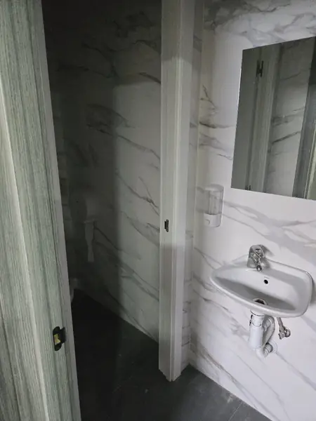 Aseo estrecho con lavabo pequeño y alicatado marmoleado