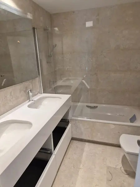 Baño reformado con doble lavabo, bañera y fontanería renovada