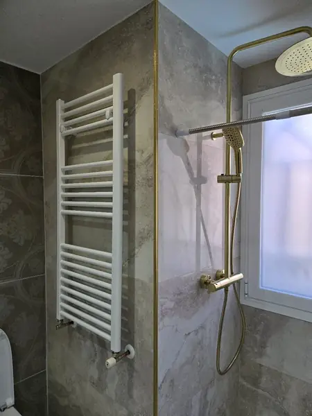Ducha con grifería en oro cepillado y radiador toallero blanco