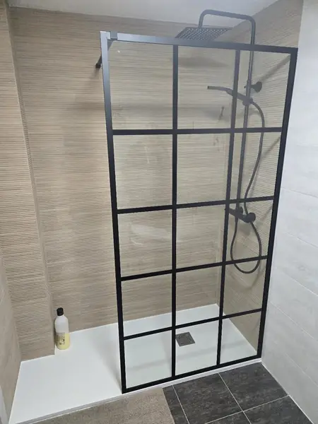 Ducha alicatada en porcelánico con mampara de cuadrícula negra y plato extraplano