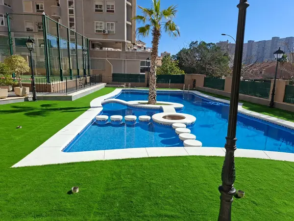 Jardín con césped artificial y piscina con isleta central