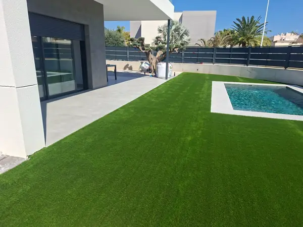 Vivienda moderna con césped artificial y piscina rectangular