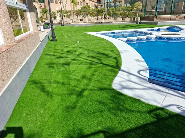 Césped artificial rematado contra el borde curvo de la piscina