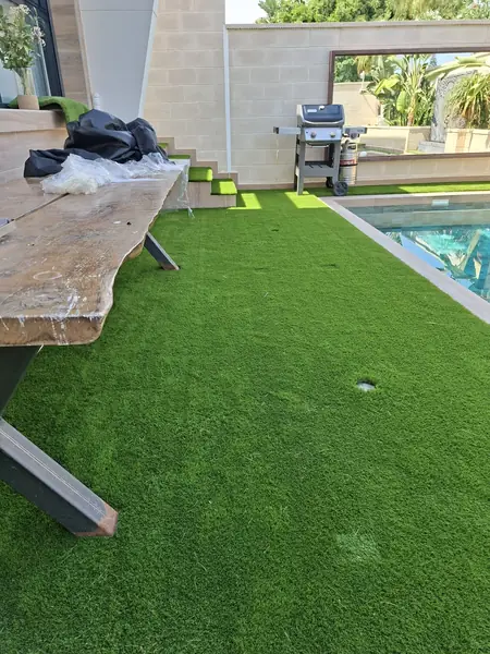 Zona de barbacoa sobre césped artificial junto a la piscina