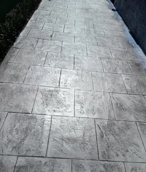 Paso lateral de vivienda pavimentado en hormigón impreso gris