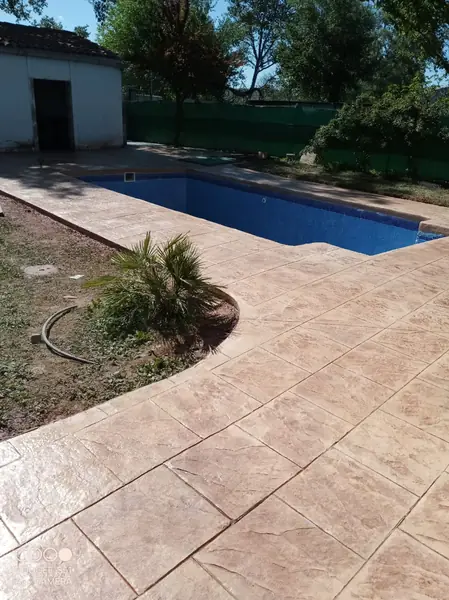 Zona de piscina pavimentada con hormigón impreso claro