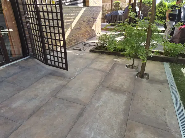 Patio con hormigón impreso y jardinera junto a la fachada