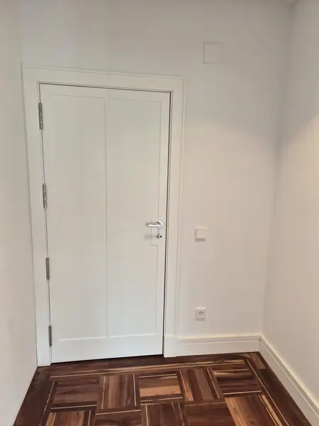 Dormitorio con puerta lacada en blanco y suelo de madera oscura