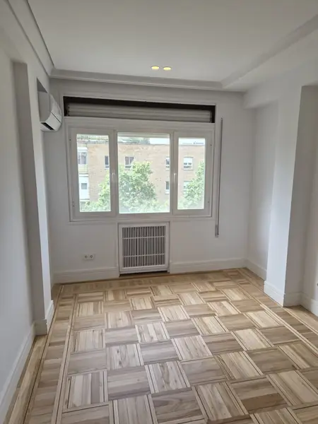 Habitación reformada con radiador y suelo de madera clara