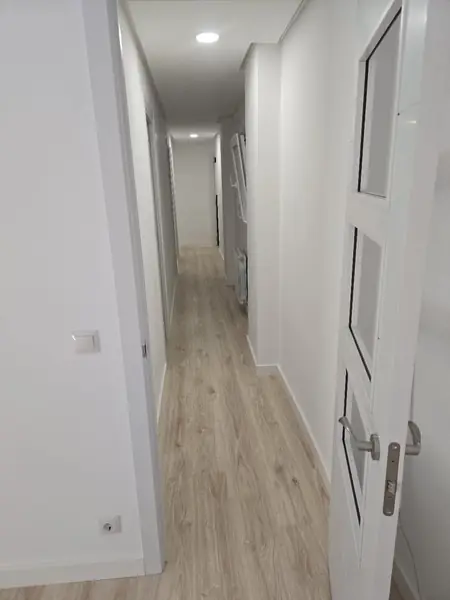 Pasillo pintado en blanco tras alisar el gotelé, con carpintería lacada