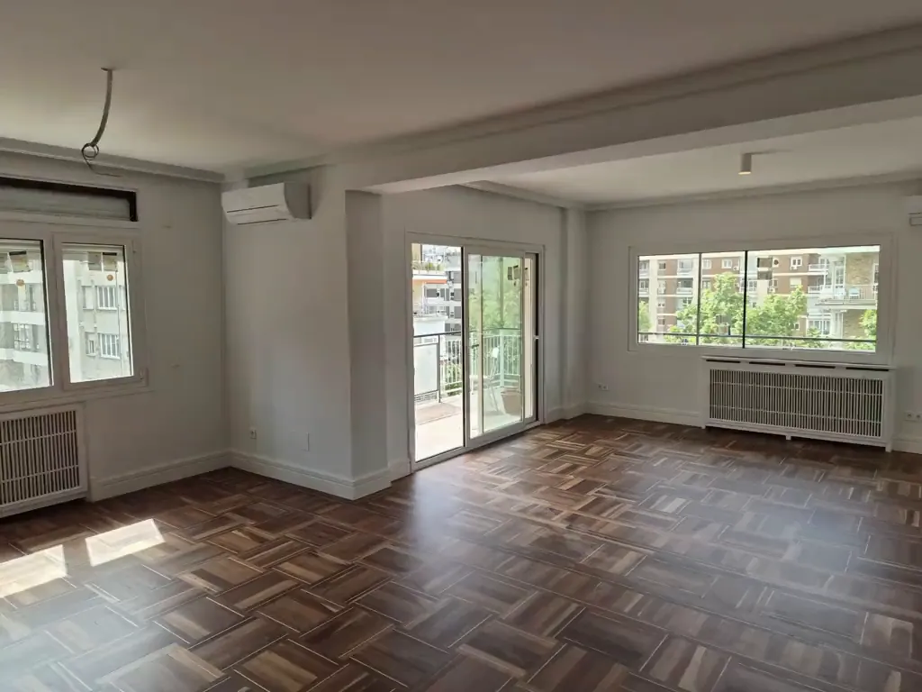 Salón reformado con parquet de nogal y ventanales al balcón